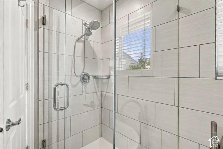 Spa-inspired shower enclosure featuring frameless glass doors, subway tile walls with contrasting grout lines, dual showerheads with handheld spray functionality, and brushed nickel fixtures