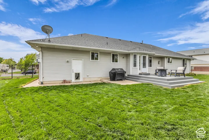 Expansive green lawn, multi-level composite deck, and light-colored vinyl siding exterior