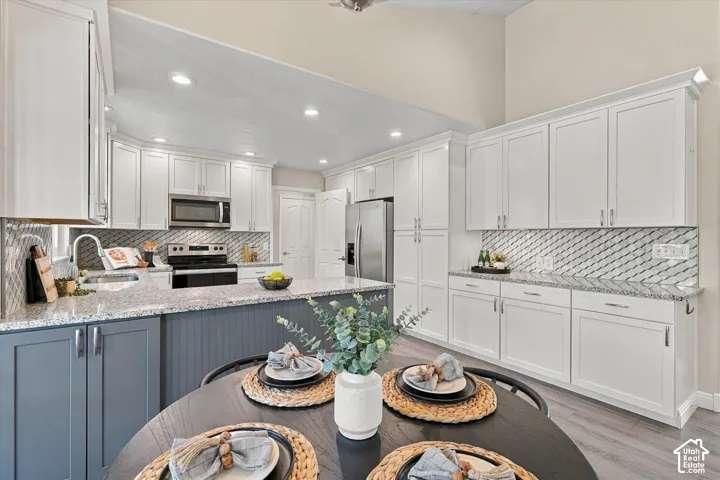 Spacious kitchen featuring white cabinetry, a large island with contrasting base, granite countertops, a diagonal tile backsplash, and recessed lighting