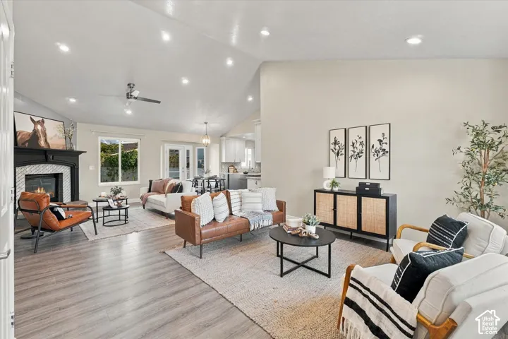 Spacious open-concept living area featuring wood-finish flooring, recessed ceiling lighting, and a fireplace with surround