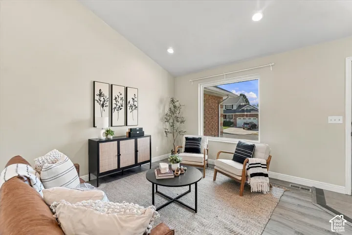 Bright living space with recessed ceiling lighting, large picture window with natural light, neutral wall finishes, wood-finish flooring, and area rug