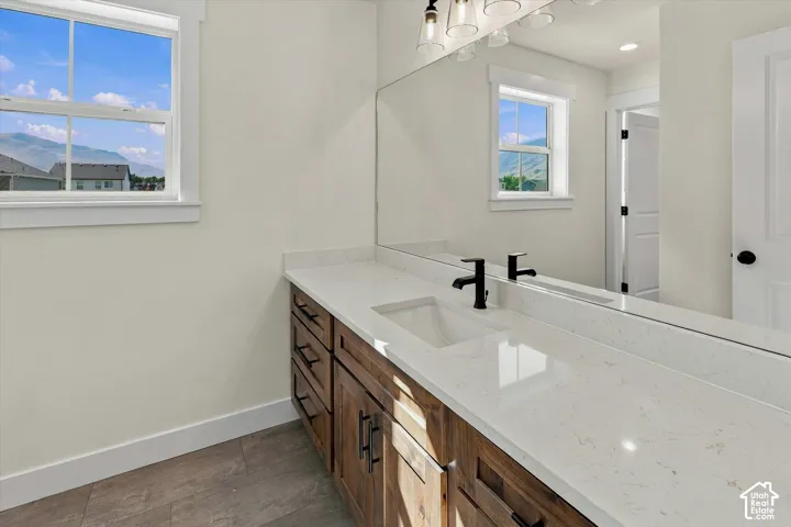 Dual-sink vanity with wood-finish cabinetry, light-toned countertop, and matte black fixtures