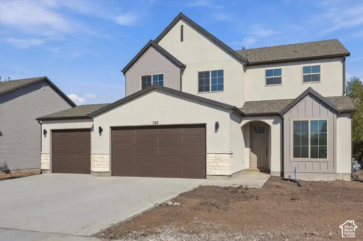 Stucco exterior with stone accents, two-car garage, arched front entry, and multiple windows