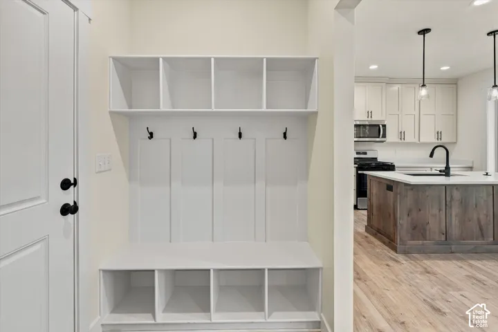 Entryway featuring built-in white shelving, coat hooks, and bench storage