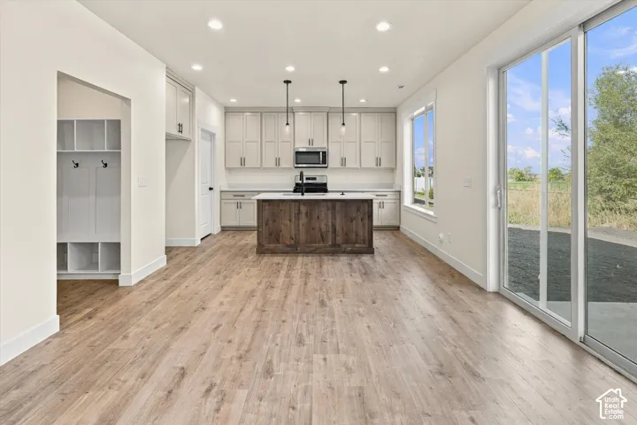 Open-concept kitchen with light cabinetry, a dark wood-finish island, and stainless steel appliances