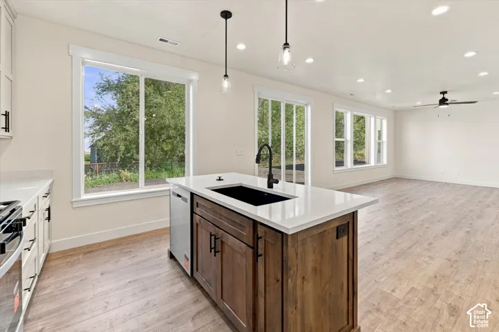 Gourmet kitchen featuring a substantial wood-finish island with a black undermount sink, white quartz countertops, and pendant lighting