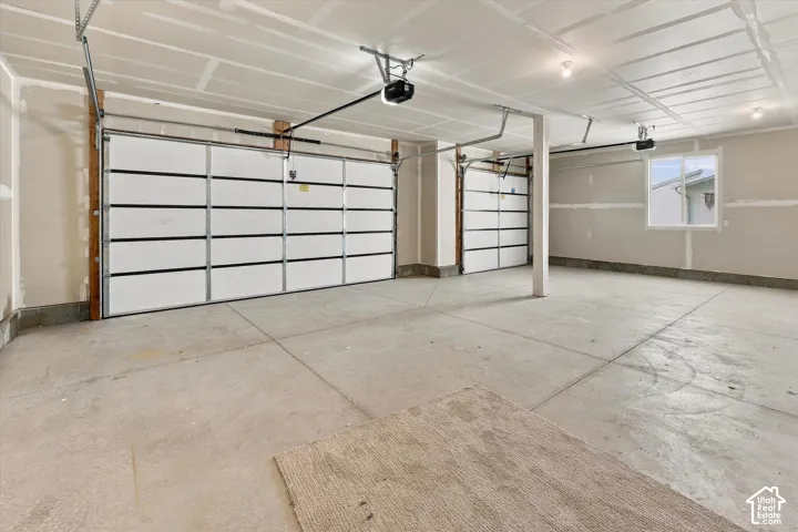 Spacious garage featuring two overhead doors, concrete flooring, and an exterior window