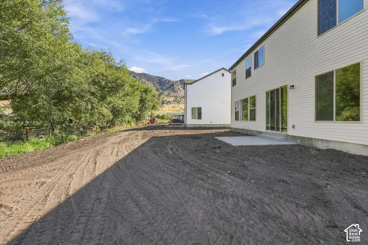Rear exterior with white siding, multiple windows, a sliding glass door, and a concrete patio