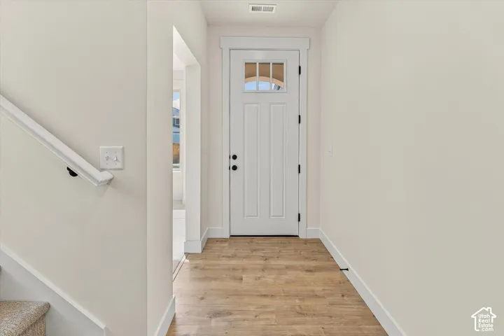 Entryway featuring wood-finish flooring, a white paneled door with an arched lite, and a white handrail
