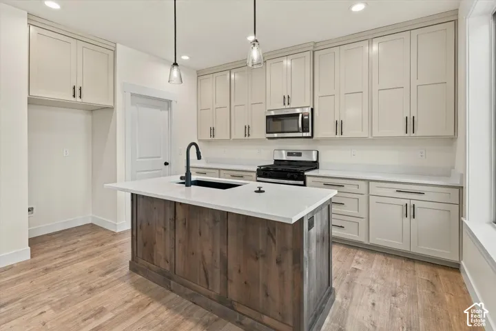 Kitchen featuring a wood-finish island, white countertops, stainless steel appliances, light-toned cabinetry, and recessed lighting