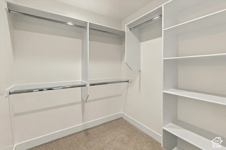 Spacious walk-in closet featuring multiple hanging rods, built-in shelving, and abundant storage solutions throughout