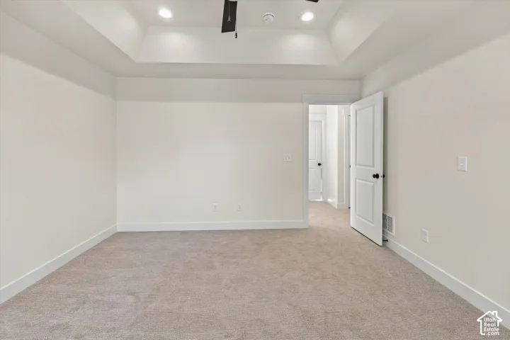 Recessed lighting, tray ceiling, neutral wall color, plush carpeting, and white trim