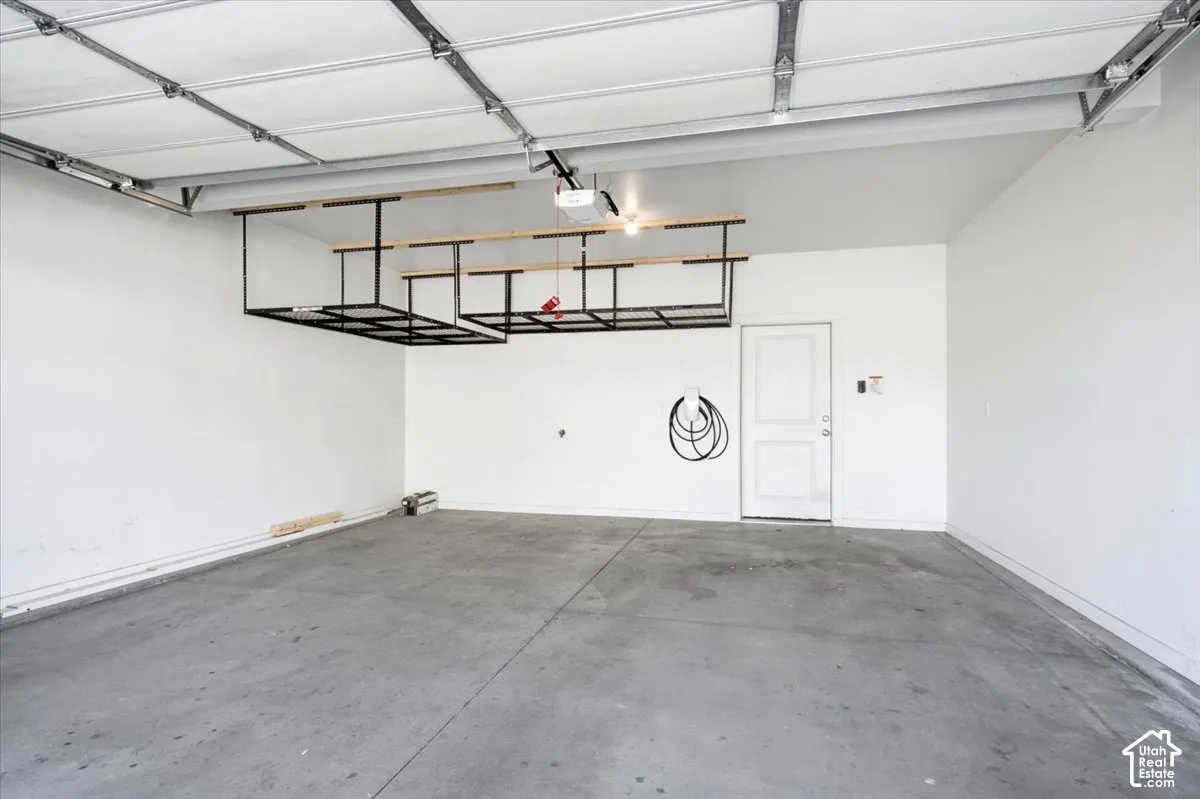 Attached overhead storage racks, concrete flooring, and a white interior door