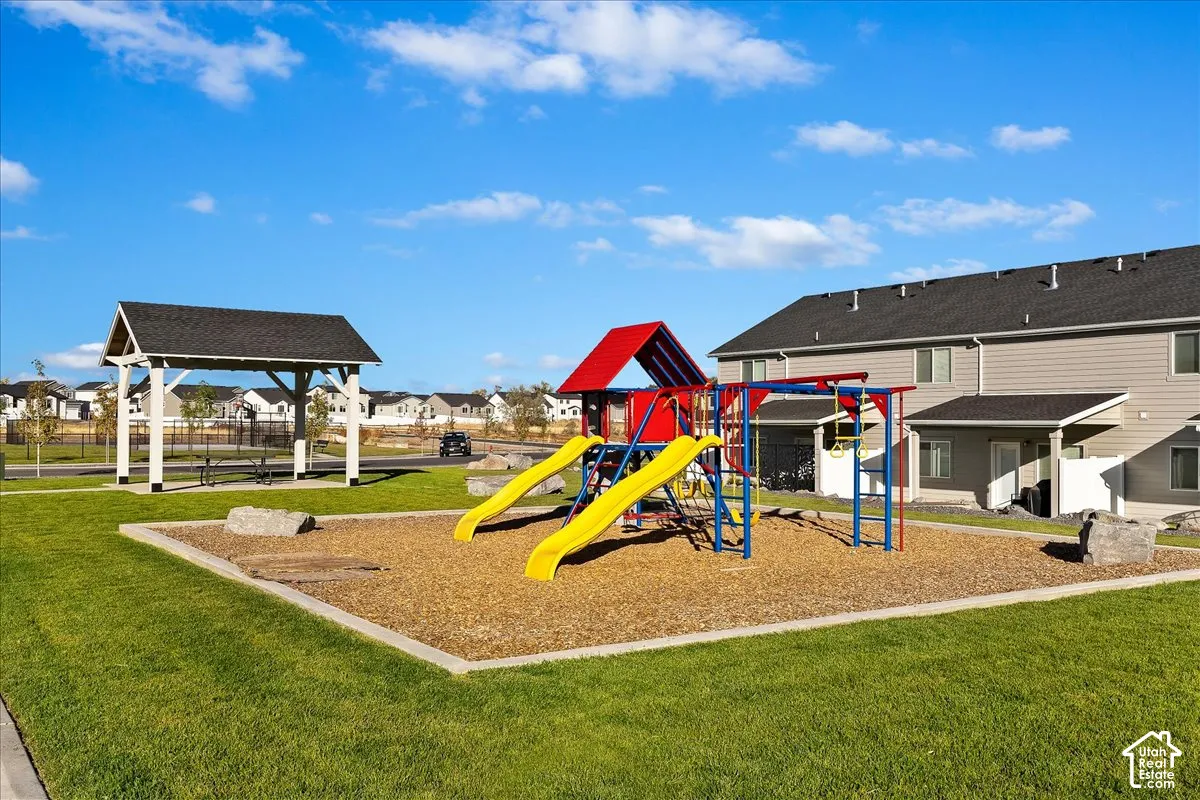 Expansive green space featuring a playground with slides and climbing structures, and a covered picnic area