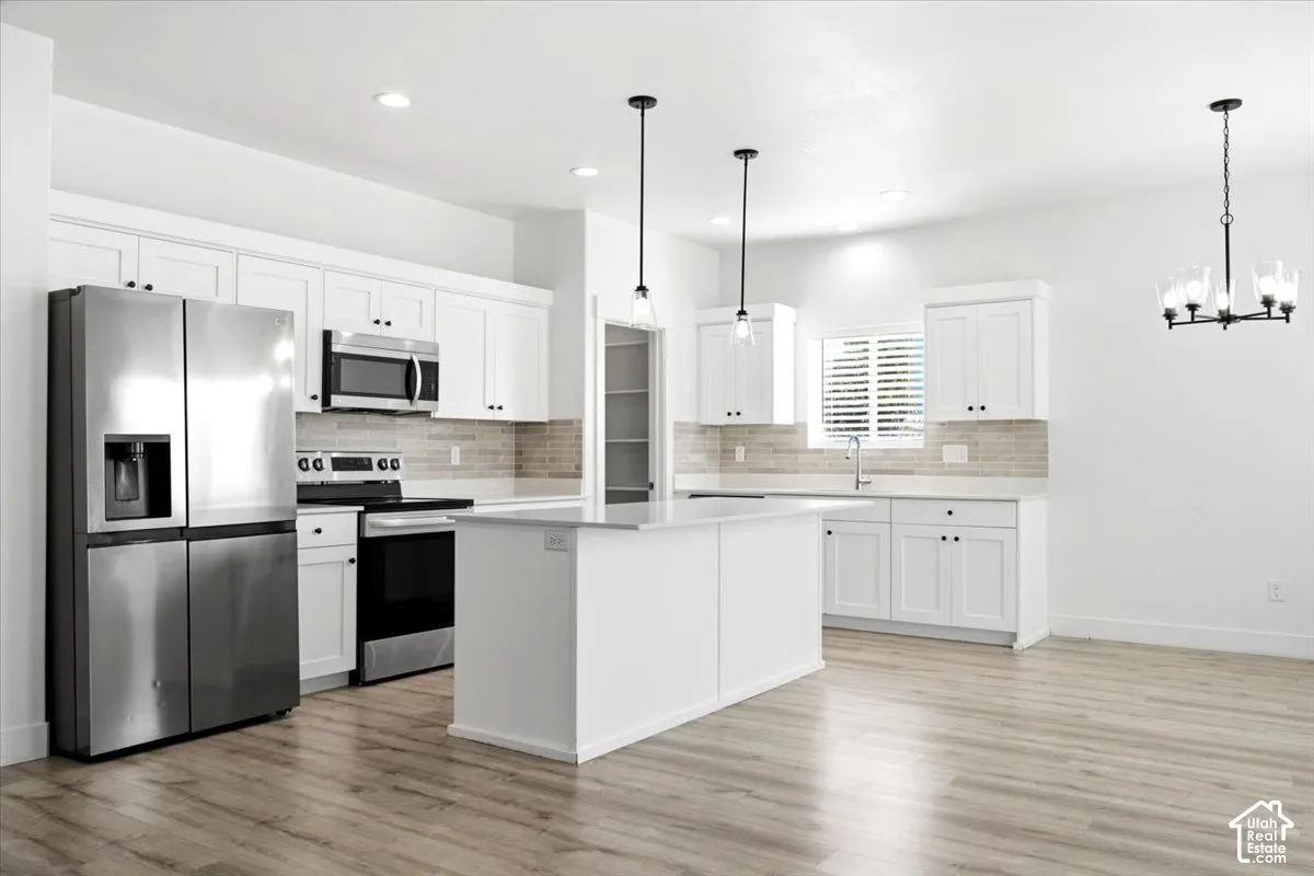 Kitchen featuring white shaker cabinetry, stainless steel appliances, a center island, wood-finish flooring, and a tiled backsplash