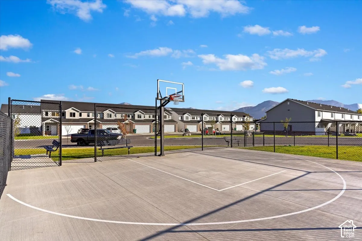 Concrete basketball court with a chain-link fence enclosure and permanent benches