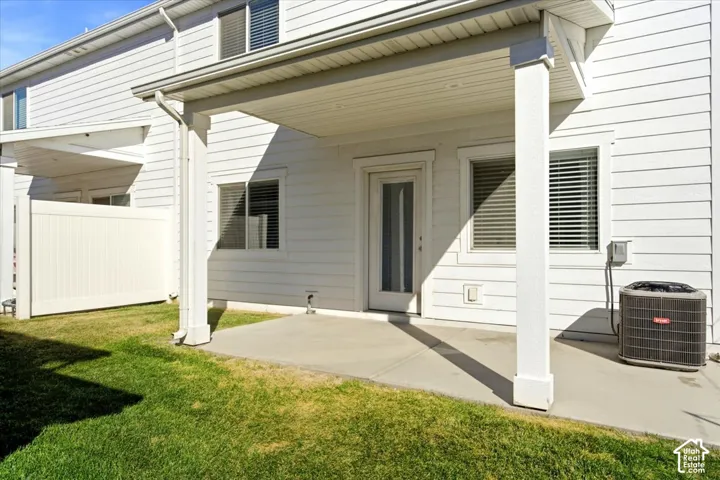 Covered patio with concrete flooring, white vinyl siding, and a partial privacy fence