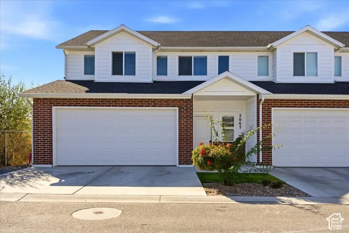 Brick and siding exterior with a two-car garage, covered entry, and manicured landscaping