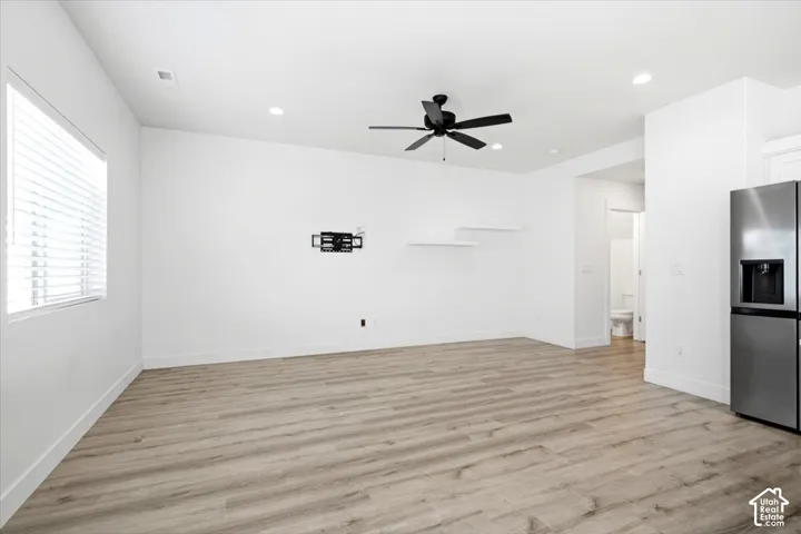 Wood-finish flooring throughout, featuring a stainless steel refrigerator, recessed lighting, and a ceiling fan