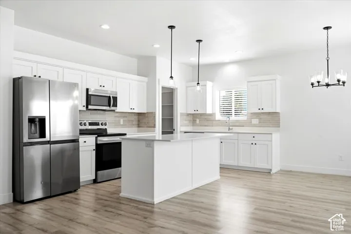 Kitchen featuring white shaker cabinetry, stainless steel appliances, a center island, wood-finish flooring, and a tiled backsplash