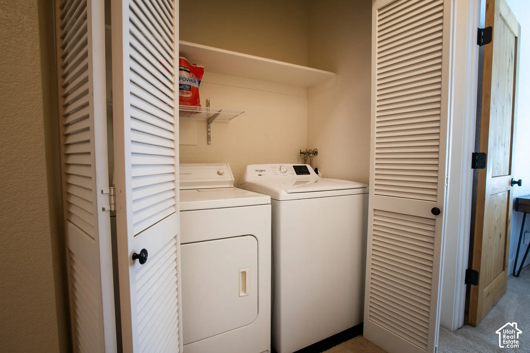Dedicated laundry room featuring side-by-side washer and dryer units, louvered bifold closet doors, built-in shelving, and a fire extinguisher for safety preparedness