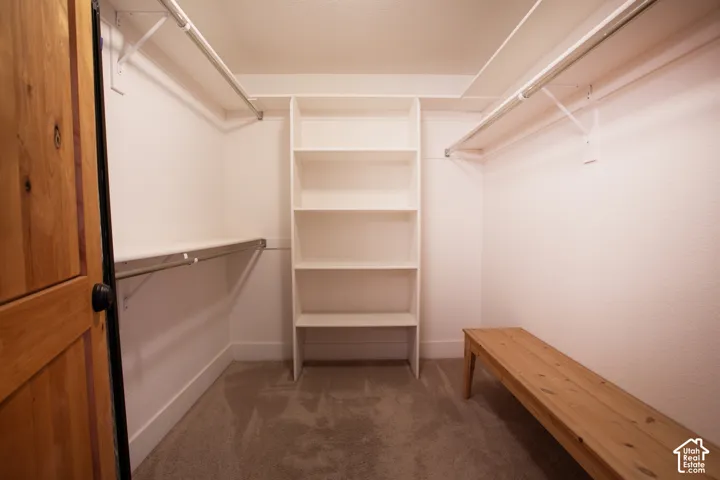 Spacious walk-in closet featuring multiple built-in shelving units, dual clothing rods with overhead storage, polished concrete flooring, and recessed ceiling lighting throughout