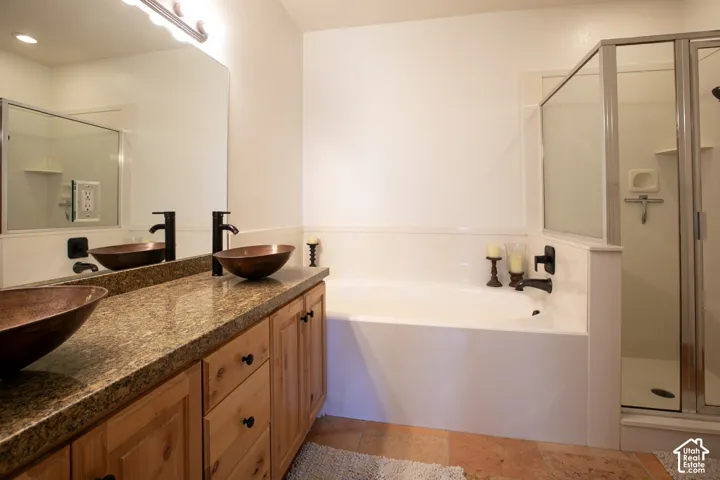 Spa-inspired primary bathroom showcasing dual vessel sinks with matte black fixtures, granite countertops, and rich wood cabinetry