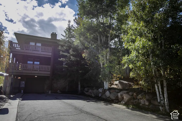 Multi-level residence featuring a sloped roofline, two balconies with wooden railings, and a ground-level garage
