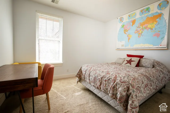 Bright bedroom with natural light from a large window, wood-finish flooring, and generous square footage