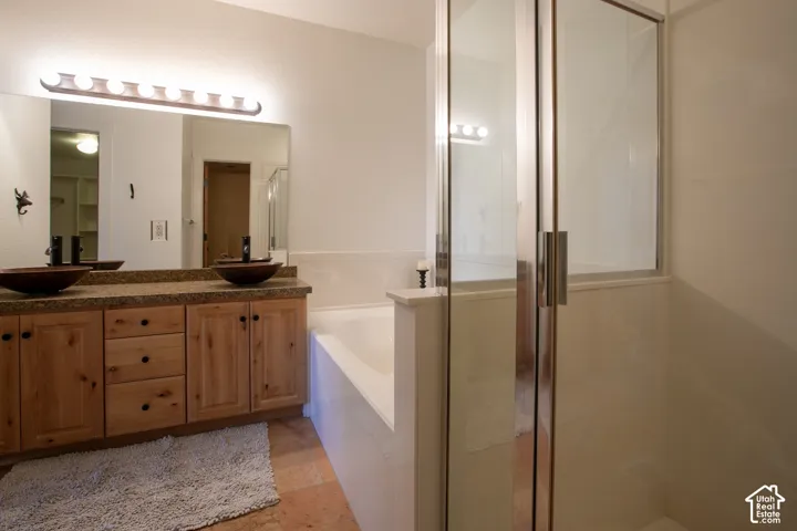 Double vanity with wood-finish cabinetry, bowl sinks, and a large wall mirror