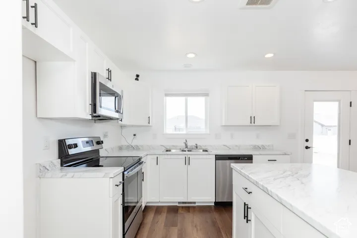 Kitchen featuring white cabinetry, stone-finish countertops, stainless steel appliances, wood-finish flooring, and recessed lighting