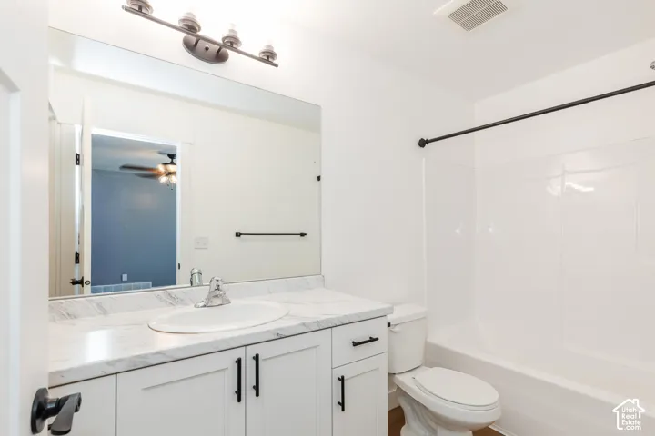 White bathroom vanity with dark hardware, a single basin sink, and a light-toned countertop