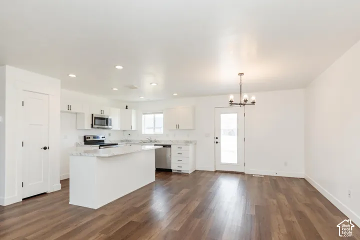 Open-concept kitchen and dining area featuring wood-finish flooring, recessed lighting, and a kitchen island with stone countertops