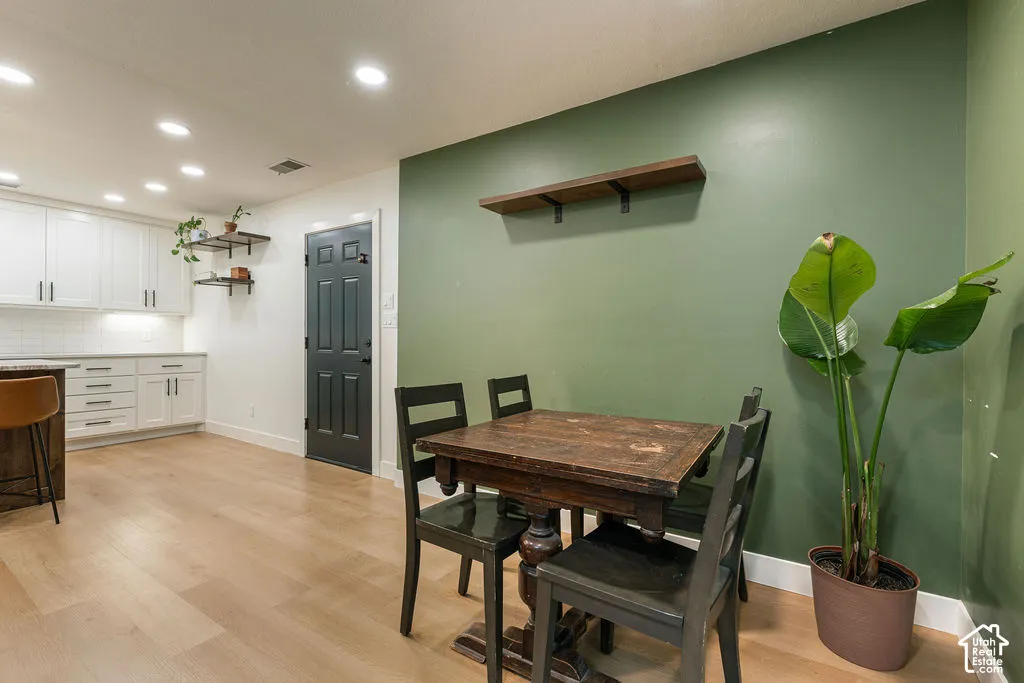 Recessed lighting, wood-finish flooring, white cabinetry, subway tile backsplash, and a paneled door