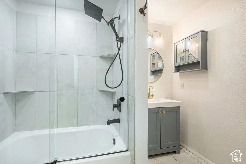 Bathtub with glass enclosure and tiled surround, featuring integrated shelving and a matte black shower system