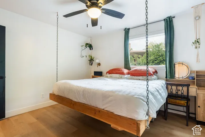 Wood-finish flooring, white walls, and a ceiling fan with integrated lighting