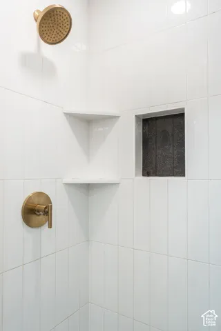 White tile shower with brass fixtures, an integrated corner shelf, and a recessed niche
