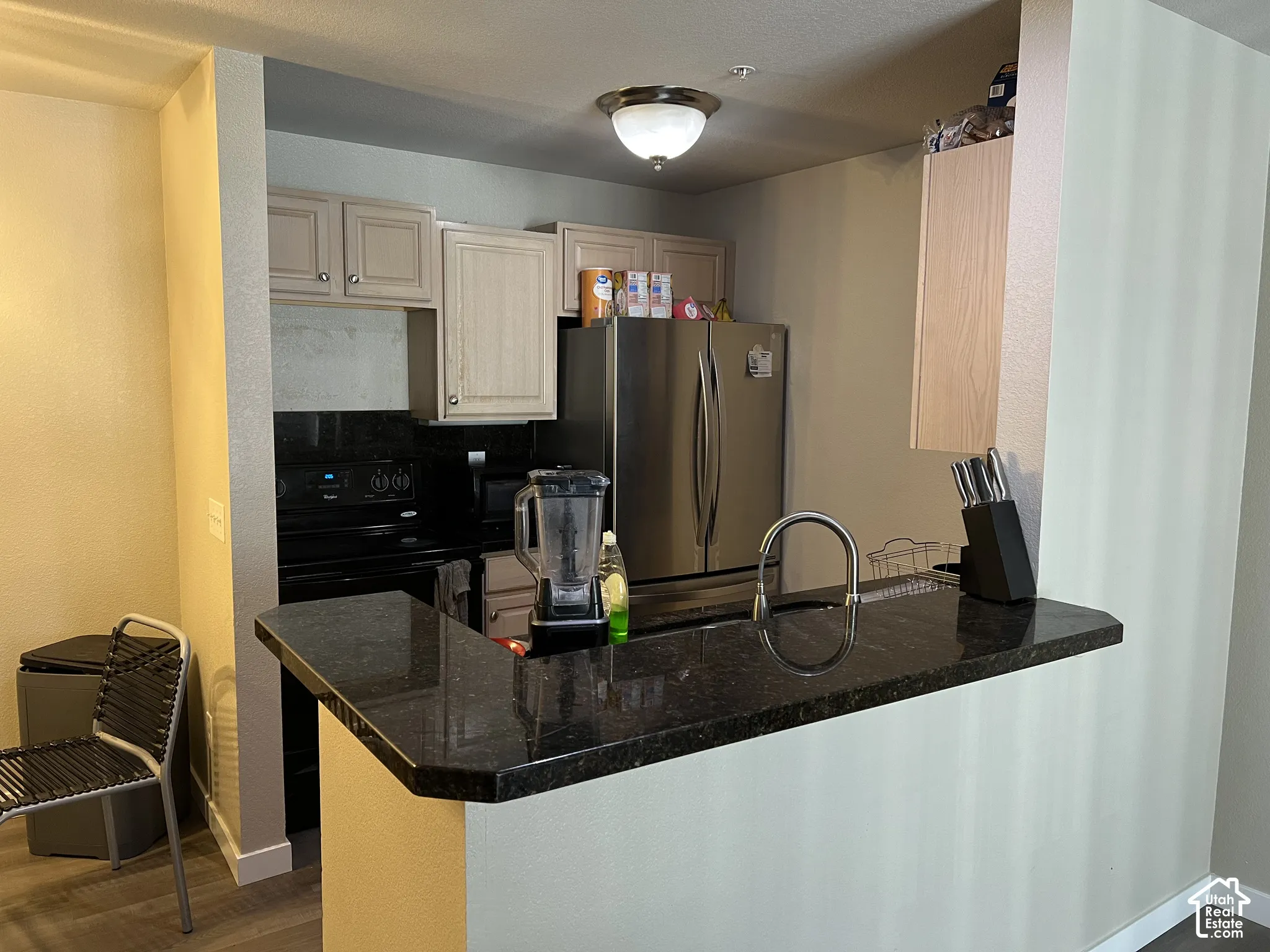 Kitchen featuring a built-in breakfast bar, dark countertops, a stainless steel refrigerator, and recessed lighting