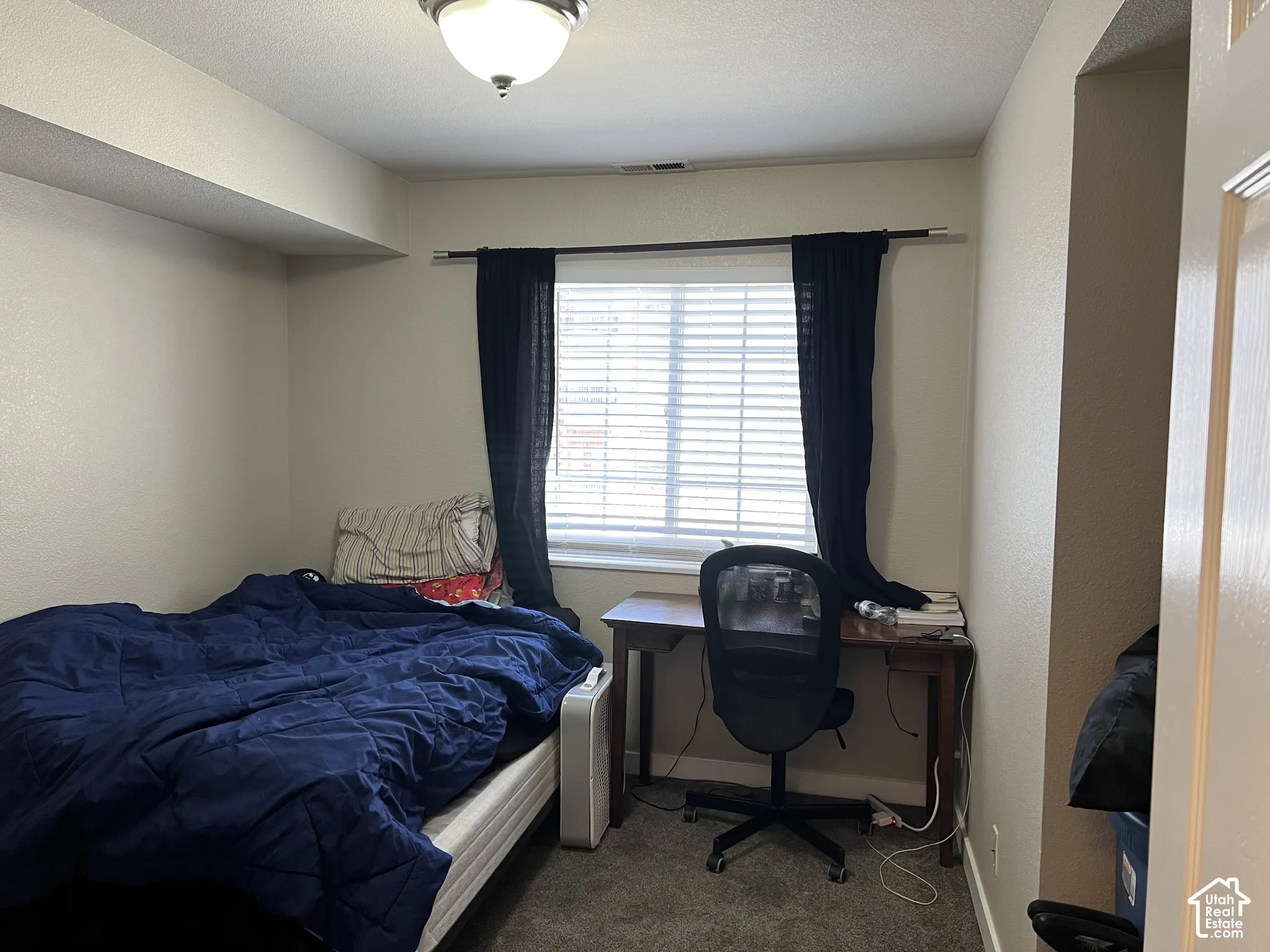 Recessed lighting fixture, textured walls, window with horizontal blinds, neutral carpeting, white interior door