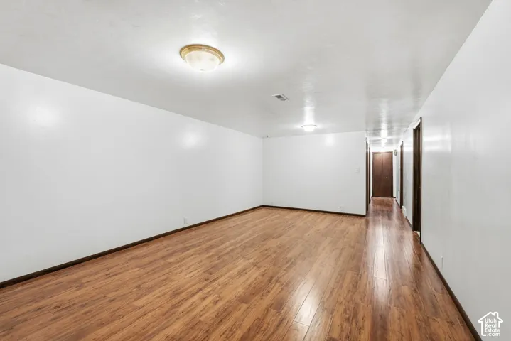 Spacious room featuring wood-finish flooring, smooth white walls, flush-mount lighting, and solid core doors