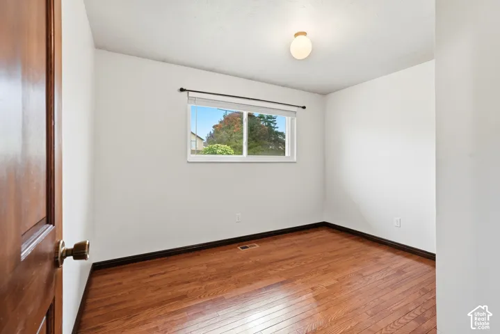 Interior room featuring wood-finish flooring, a horizontal sliding window, a solid wood-panel door, and a spherical flush-mount light fixture