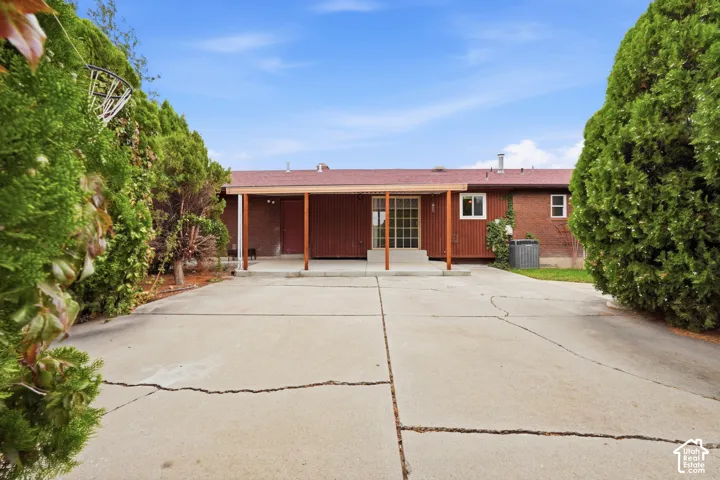 Brick exterior, concrete driveway, and covered patio featuring wood-beam supports