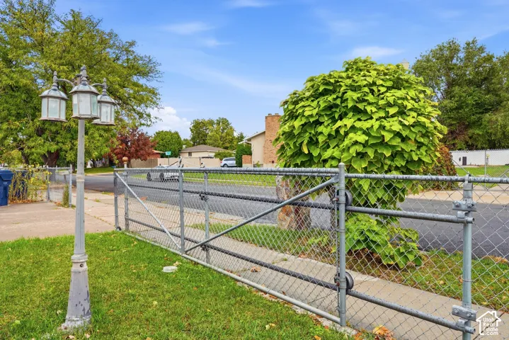 Metal chain-link perimeter fencing, decorative triple-head pedestal lamp post, and mature greenery