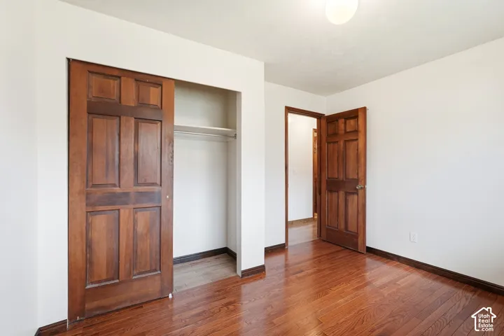 Wood-finish flooring, six-panel wood doors, and a built-in closet with integrated shelving and hanging rod