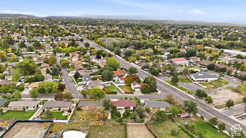 Aerial perspective of a suburban setting featuring established vegetation, mature trees, a grid of residential streets, and regional mountain terrain