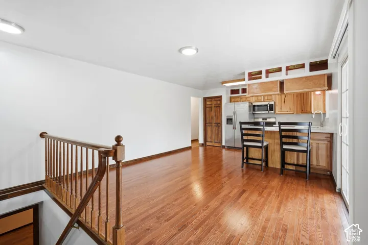 Wood-finish flooring, natural wood cabinetry, stainless steel appliances, recessed lighting, and wooden staircase railing