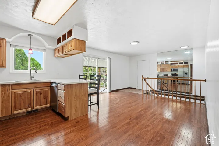 Kitchen featuring wood cabinetry, solid surface countertops, wood-finish flooring, sliding glass door, and wooden staircase railing
