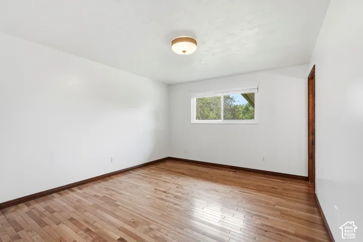 Room featuring wood-finish flooring, white walls, a flush-mount drum ceiling light, and a single-pane horizontal sliding window