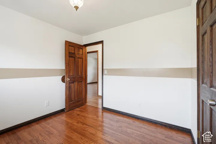 Interior room featuring wood-finish flooring, solid wood six-panel doors, and a neutral wall treatment with horizontal banding