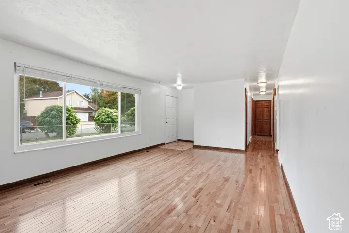 Living area featuring wood-finish flooring, a large picture window, recessed ceiling lighting, and solid wood interior doors